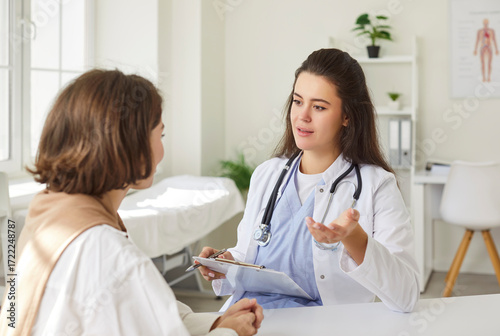 Foto Cheerful and friendly doctor or nurse conducts a conversation with a patient during a medical visit in a hospital office