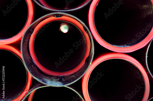 closeup of red plastic pipes with their insides small light on the end