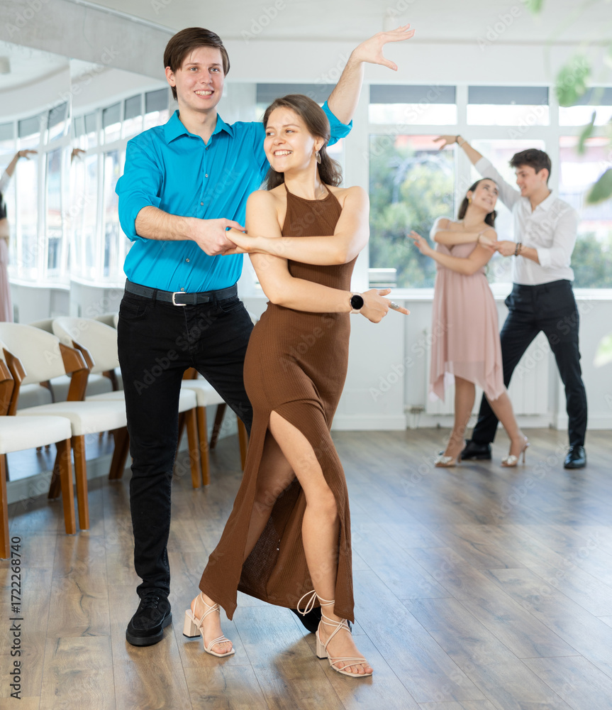 Naklejka premium Young couples learning to dance latin american dances in a dance studio