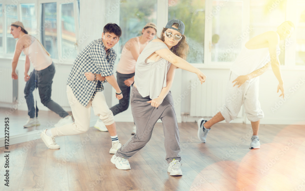 Obraz premium Stylishly dressed young people learn to dance hip-hop and breakdance in a dance studio