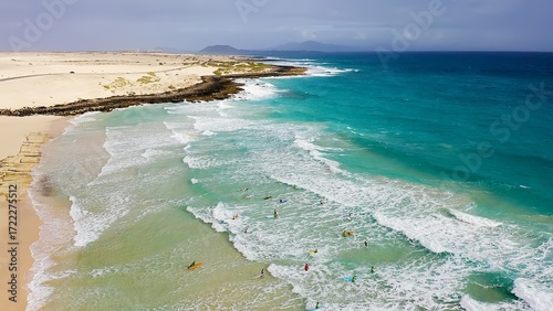 Aerial view of a crowd of surfers enjoying the waves on the beach of Corralejo, Fuerteventura Island, Spain.