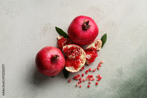 Obraz na płótnie Fresh ripe pomegranates with seeds and leaves on grunge background