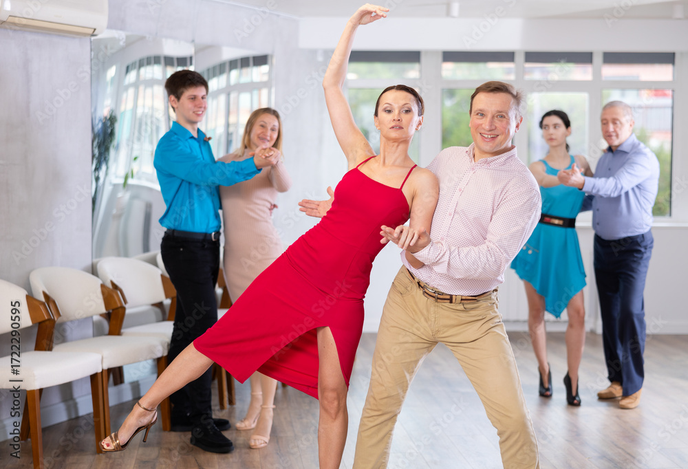 Naklejka premium Happy couple of amateur dancers practicing elegant slow foxtrot, skillfully performing support in dance studio ..