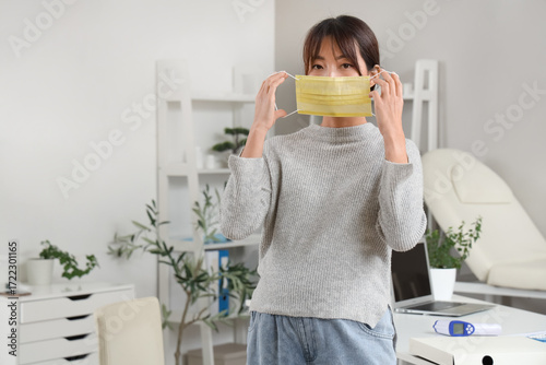Pregnant Asian woman puttin...