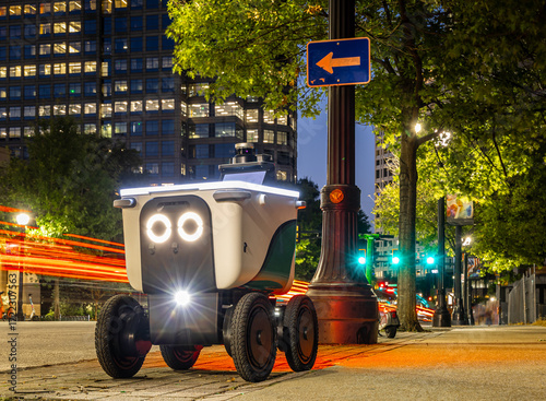 Autonomous delivery robot on Atlanta street at night with headlights and glowing eyes