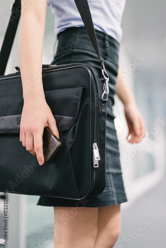 Businesswoman holding phone and laptop bag