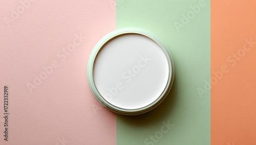 A pale-green circular container with a white interior sits on a pastel background of pink, green, and orange