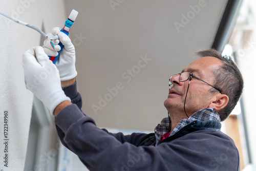 An electrician removes insulation from a copper wire. Working with the tool. Professional electrician working on electrical system, preparing copper wires for connection.