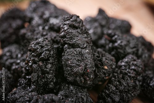 Deep purple dried mulberries closeup - healthy superfood berries with natural wrinkled texture
