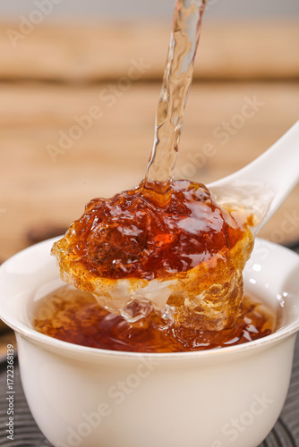 Honey dripping from wooden spoon with honeycomb in cup - natural health remedy for throat and tea