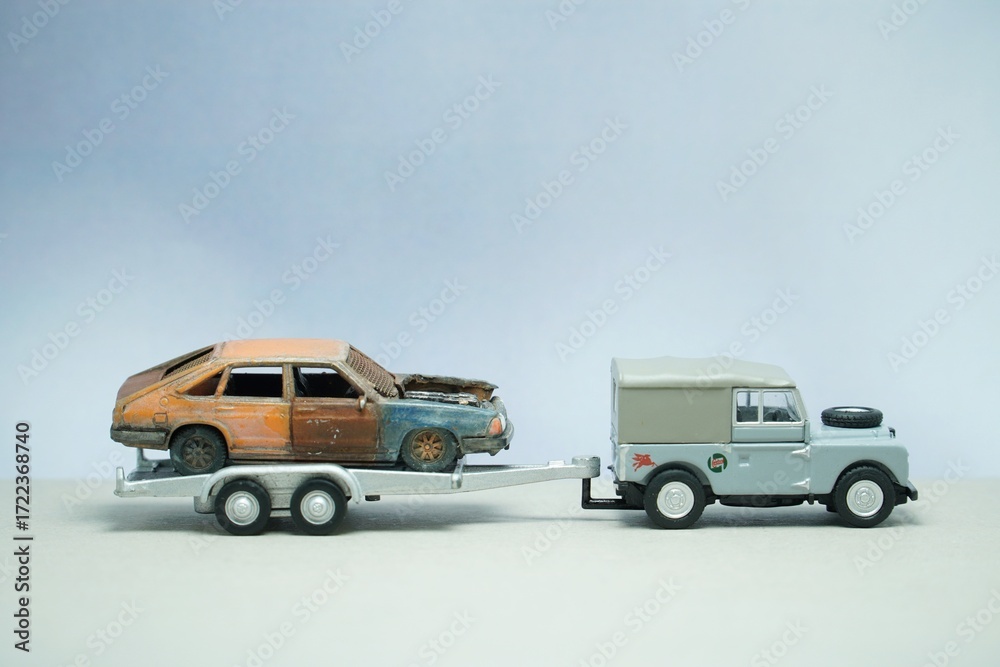 Fototapeta premium Mini toy of action figure at outdoor with blurred background. Miniature photography concept design. Minifigure of worker character with damage car at towing truck.