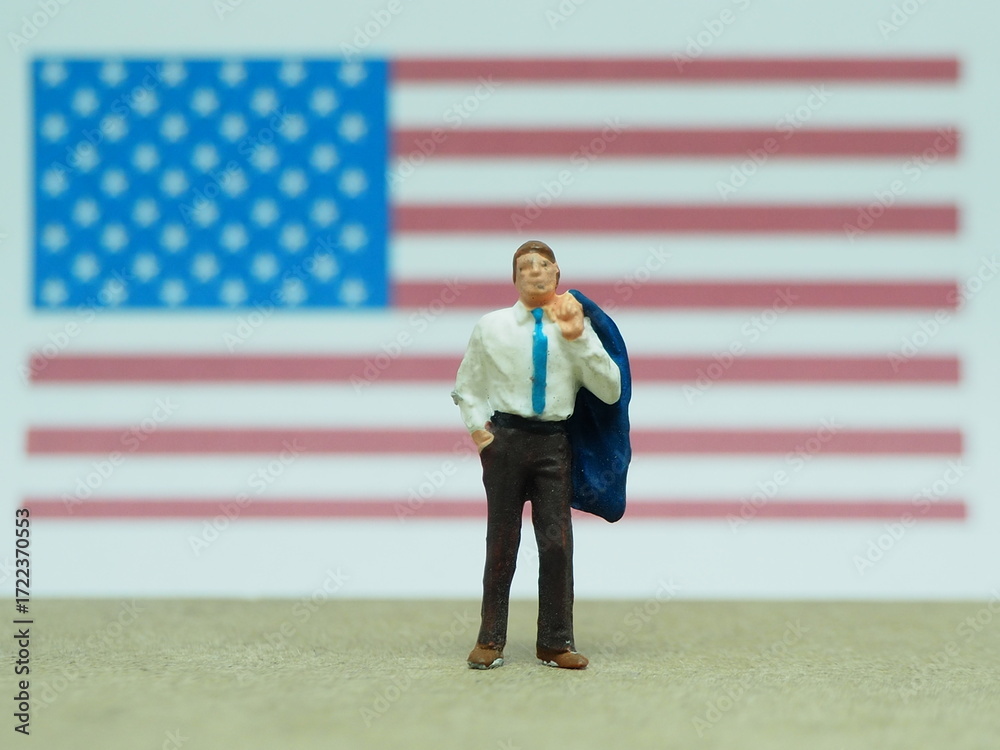 Obraz premium Mini toy of action figure at table with blurred background. Miniature photography concept. Businessman with United States of America flag as a background.
