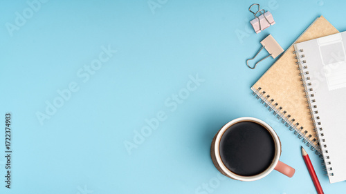 Start your day right with a cozy coffee break, notebook, and pen on a clean blue desk, perfect for planning and creative ideas in a calm workspace