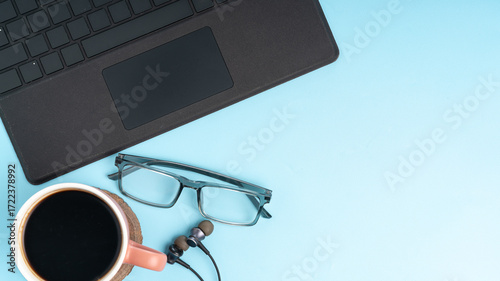 Inspiring workspace with coffee, laptop, and glasses on a light blue background offering space for your message or text perfect for professional projects