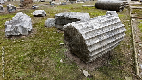 Rome, Italy - 11 January 2025. Fragmented marble columns rest on a grassy patch at Trajan's Forum, part of the ruins from the Roman Empire's architectural legacy.