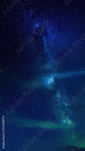 A mesmerizing nightscape reveals the luminous Milky Way stretching across a dark blue sky, sprinkled with countless stars and ethereal cloud forms