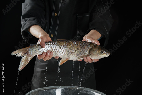 Принти на полотні Fisherman holding fresh caught fish over bucket with water dripping from live ca