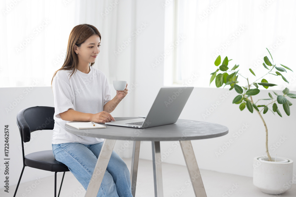 Fototapeta premium Young woman working on laptop at home in bright minimal interior
