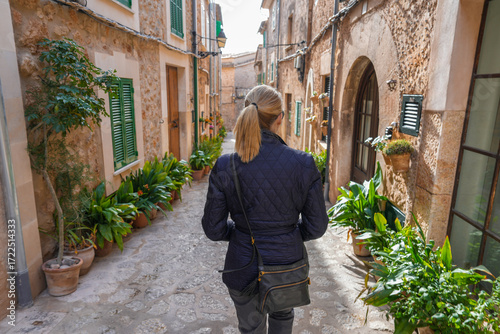 Woman walking through street filled with potted plants in Valldemossa Spain