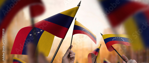 Venezuela flags in their hands on a blurred urban background