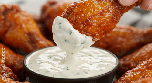 Close-up of spicy chicken wings being dipped into blue cheese dressing