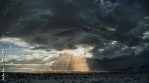 Dramatic winter landscape with sunbeams piercing through dark clouds