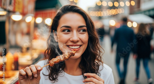 Happy woman enjoying street food at night market eating grilled meat skewers delicious tasty food travel experience