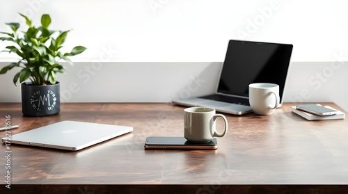 Minimalist office desk setup with modern laptop, coffee mug, smartphone, and potted plant on a clean white background, bright natural lighting, top view.