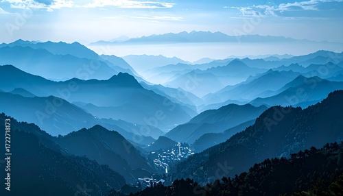A serene mountain vista featuring layered, rolling hills under a pale blue sky, creating a peaceful and expansive landscape