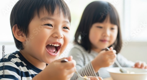 Happy young asian boy and girl eating breakfast together at a table