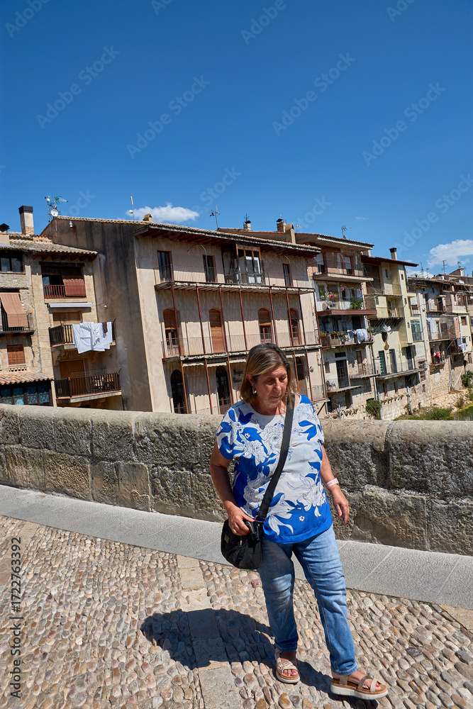 Fototapeta premium A mature woman on vacation in Valderrobres, Teruel, connecting with the history and serenity of the rural Mediterranean environment