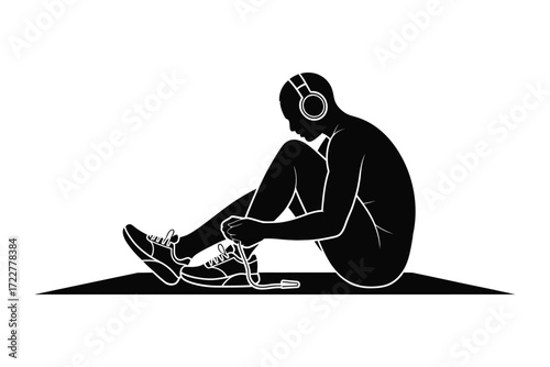 Silhouette of a person tying shoelaces while listening to music