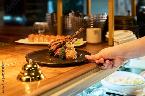Billede på lærred Caucasian young adult male hand serving plate with grilled lamb chops and vegeta