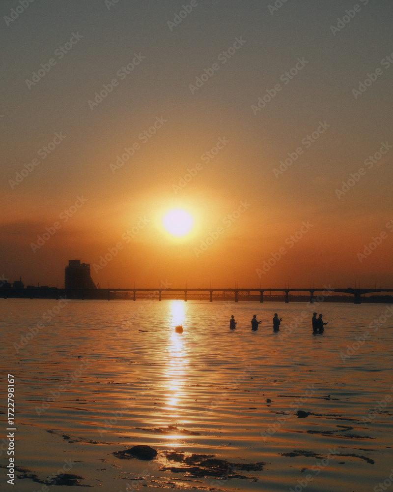 Naklejka premium Golden hour on the beach. The image conveys a sense of calm and serenity as people enjoy the beauty of a sunset in nature, in harmony with the surrounding landscape.