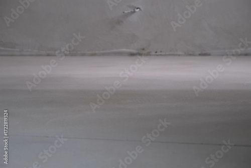 Smooth cement floor screed in rough finishing apartment overhaul process. Construction, reconstruction, restoring works in unfinished building. Concrete gray floor and walls in flat.