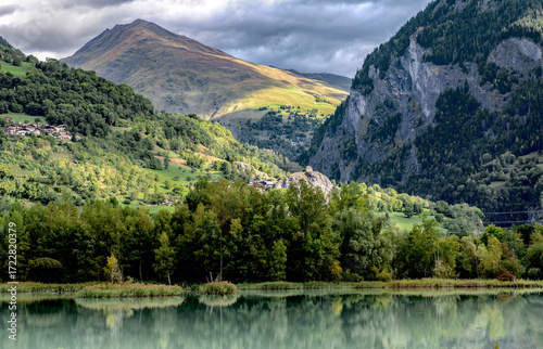 mountain lake in mountainous landscape bordered by forest under cloudy sky in french alps