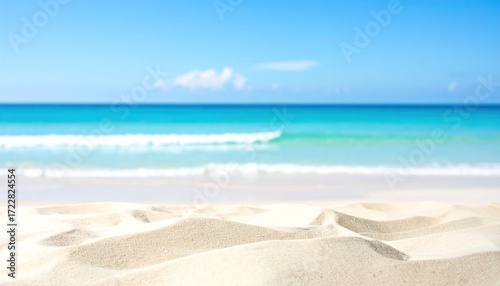 Blurred seascape view from the sandy beach, showing turquoise water under a clear blue sky with soft waves