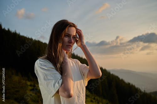 Schilderij op canvas Close-up portrait of a young woman standing on a mountain at sunrise