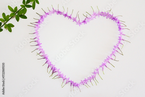 A love pattern made of purple flowers, green plant, copy space, close-up