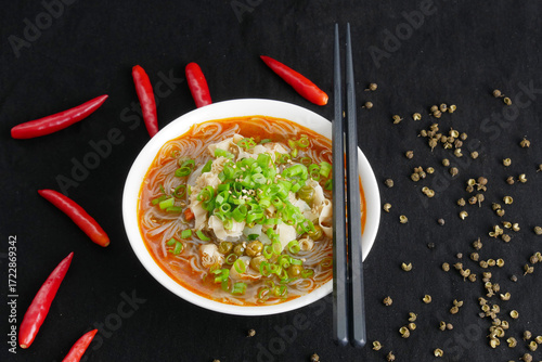 Close-up hot and sour rice noodle soup on black background, top view
