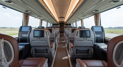 The luxurious interior of a modern coach bus, showcasing rows of comfortable seating with individual entertainment screens and ample legroom, ready for passenger travel.