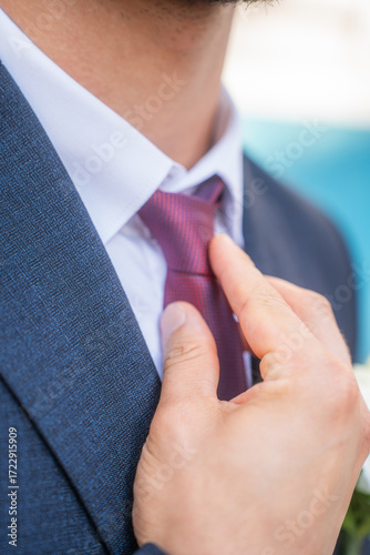 Man in a suit fixing his tie.