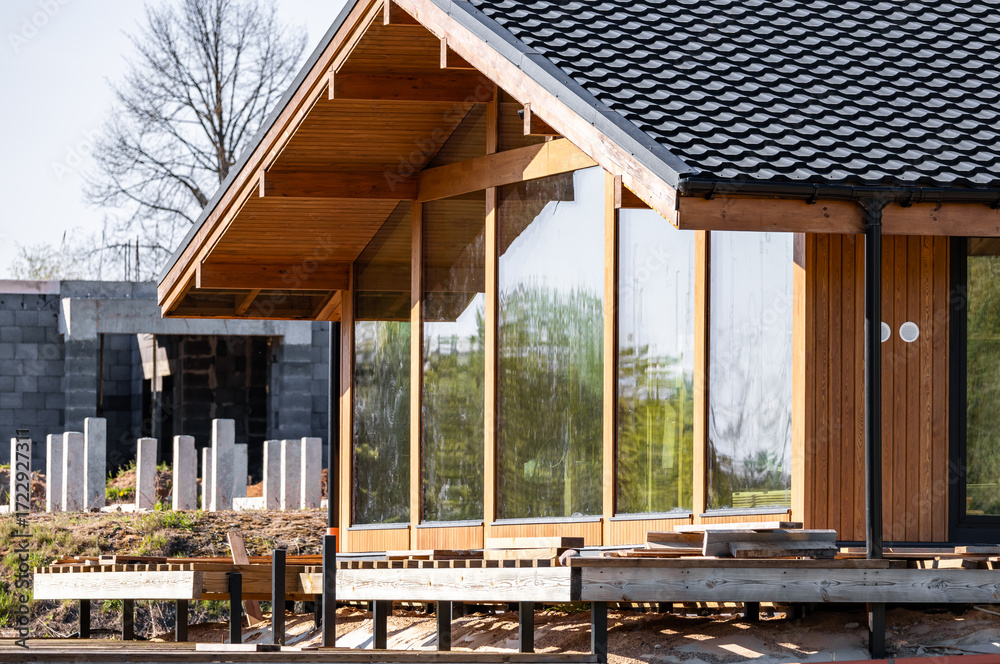 Fototapeta premium Modern frame house with panoramic windows on a pile foundation. Construction of a modern frame house on stilts.