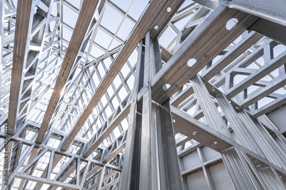 Obraz premium New technology steel frame for construction. New home under construction using steel frames against cloudy sky