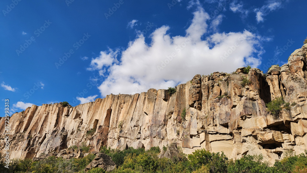 Fototapeta premium Carved over millennia by Melendiz Stream, the rocky cliffs in Ihlara Valley offer hikers a spectacular mix of natural beauty and historical wonders of early Christian churches carved in