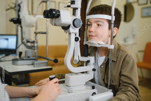 Boy undergoing vision diagnostics with slit lamp in ophthalmology clinic