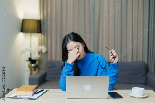 Tableau sur toile Young woman working from home experiencing fatigue and eye strain, rubbing her e