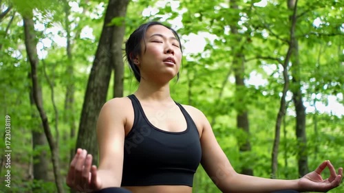 A woman meditates peacefully in a lush forest, exuding serenity and tranquility.