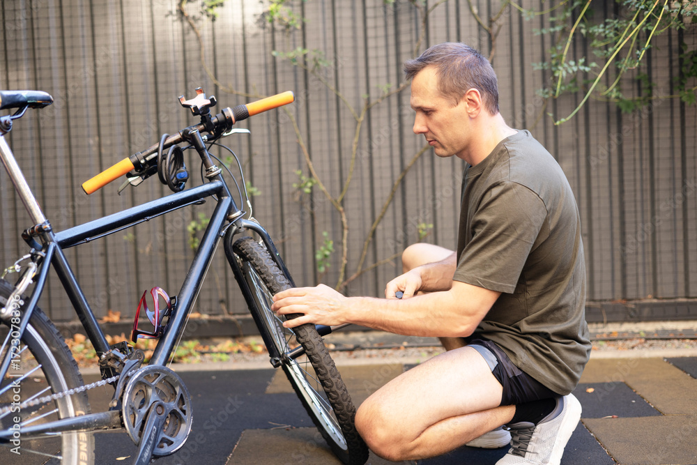 Obraz premium Caucasian male cyclist checking his road bike tire. Part of bicycle. Close-up of male hands fixing bike Wheel. Bike maintenance.