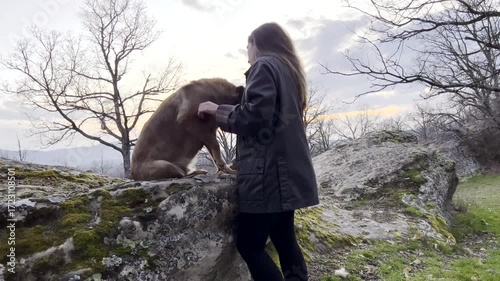 Woman brushing and petting her dog in nature